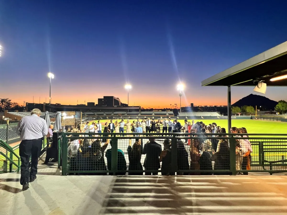 A group of people attending an event beside the baseball field
