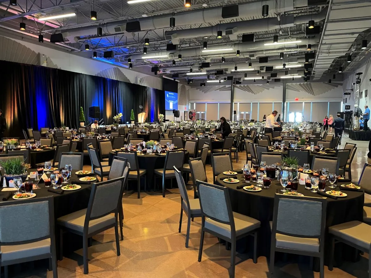 a room filled with circular tables holding plates of food and drinks with chairs surrounding them